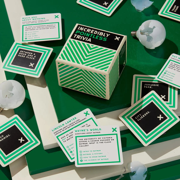 Green and white 'Incredibly Pointless Trivia' game box with cards on a green surface.