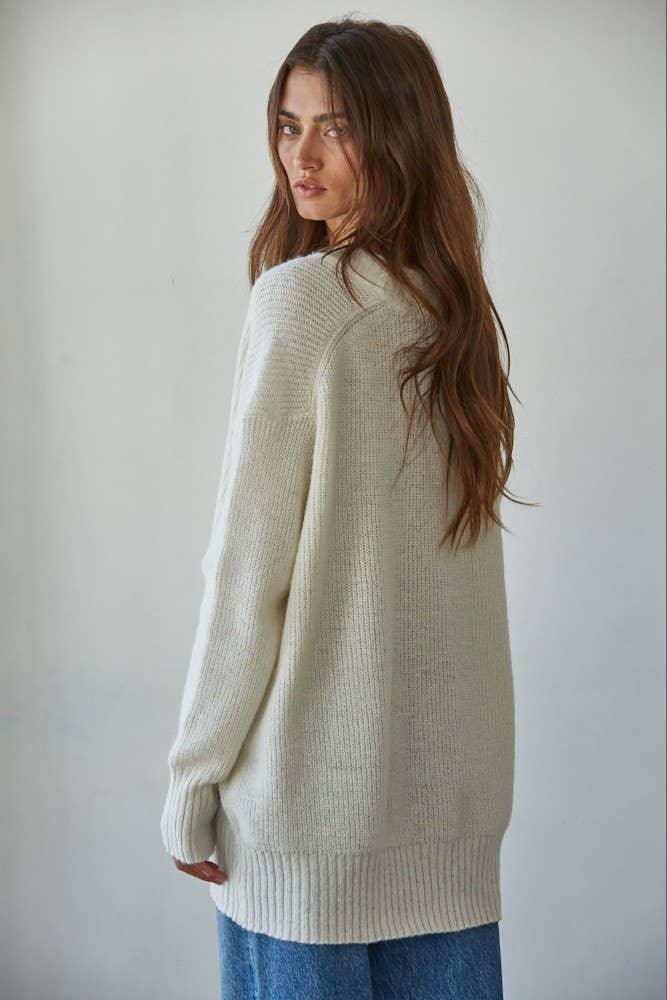 Woman wearing a cream sweater against a plain background