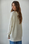 Woman wearing a cream sweater against a plain background
