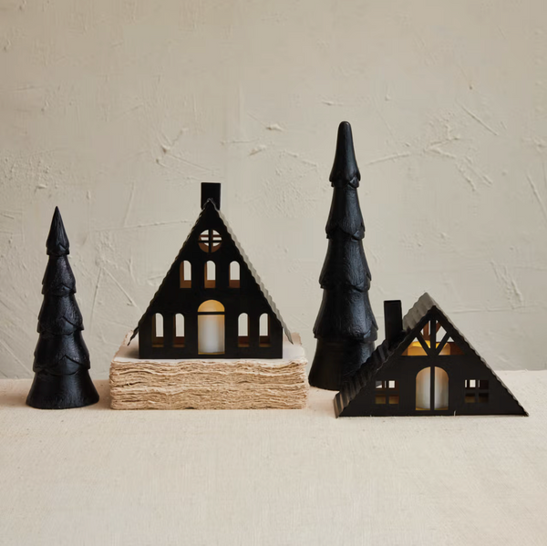 Decorative black house and tree figurines on a neutral background