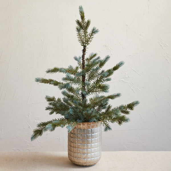 A square metal planter with a debossed grid pattern and a distressed pewter finish, containing a potted plant with green branches and pine cones.