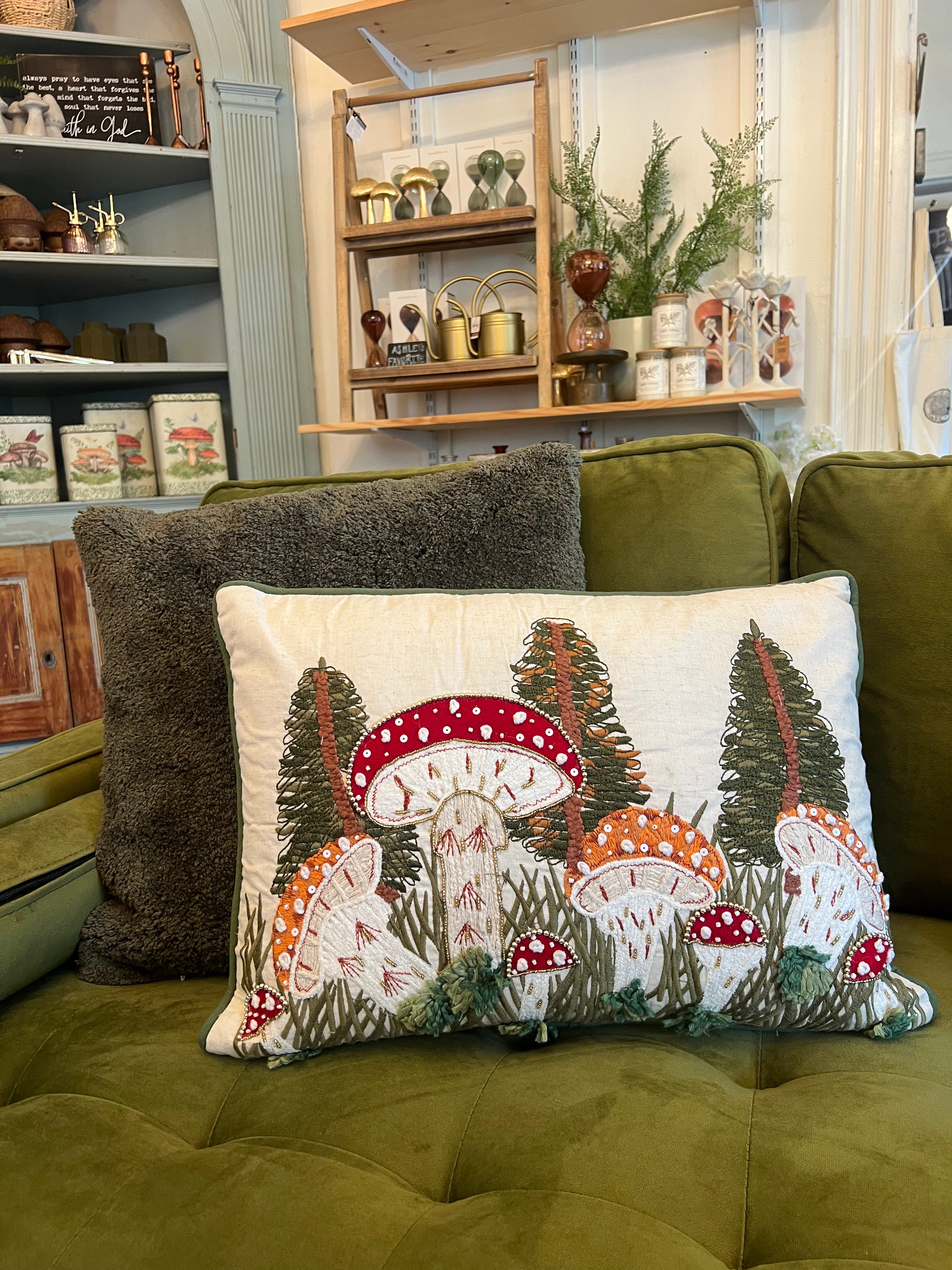 Decorative pillow with mushroom design on a green couch in a cozy living room.