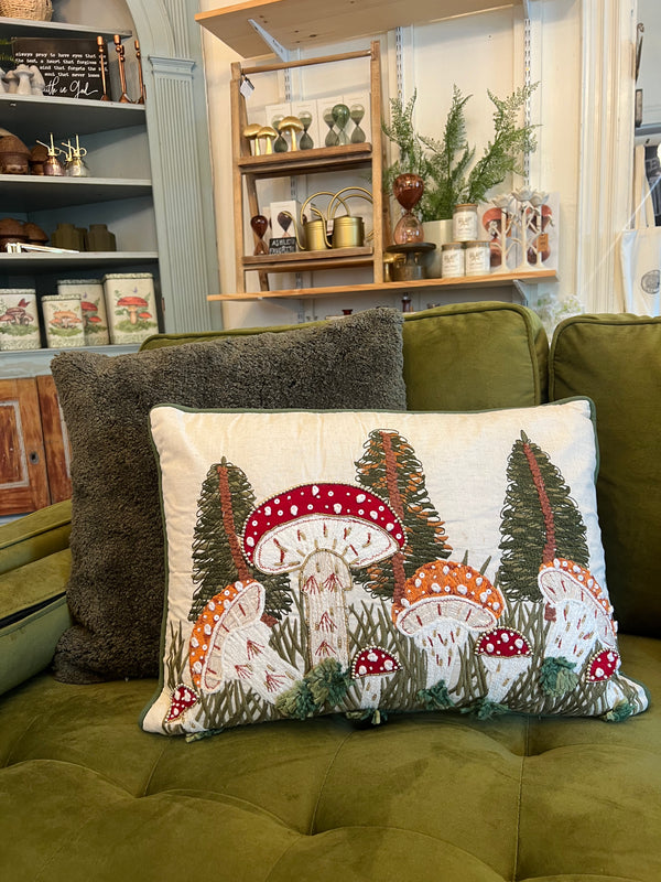Decorative pillow with mushroom design on a green couch in a cozy living room.