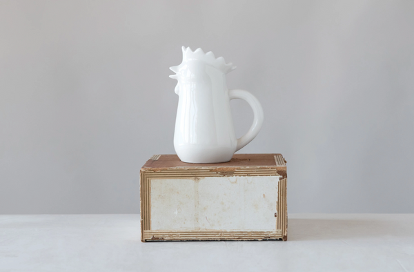 White ceramic pitcher on a wooden box against a gray background