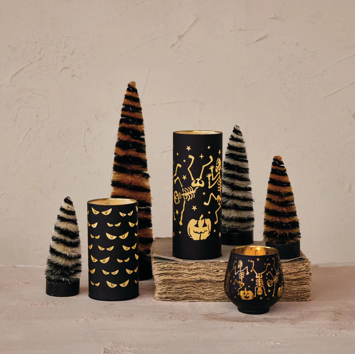 Decorative candles and trees with Halloween-themed designs on a neutral background