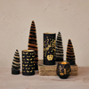 Decorative candles and trees with Halloween-themed designs on a neutral background