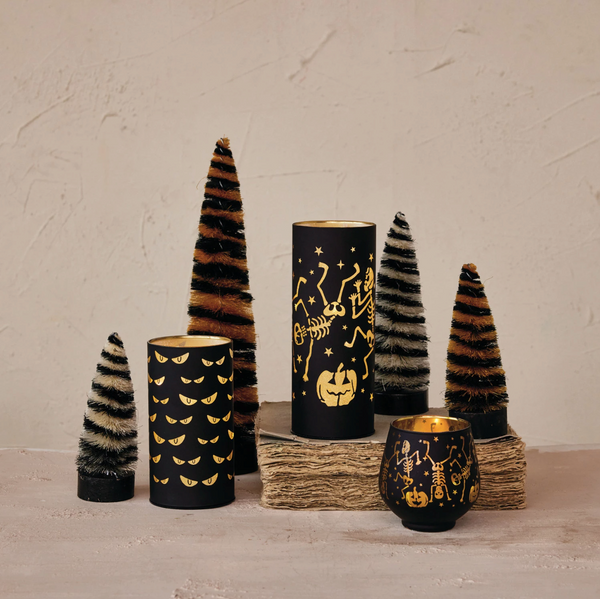 Decorative candles and trees with Halloween-themed designs on a neutral background