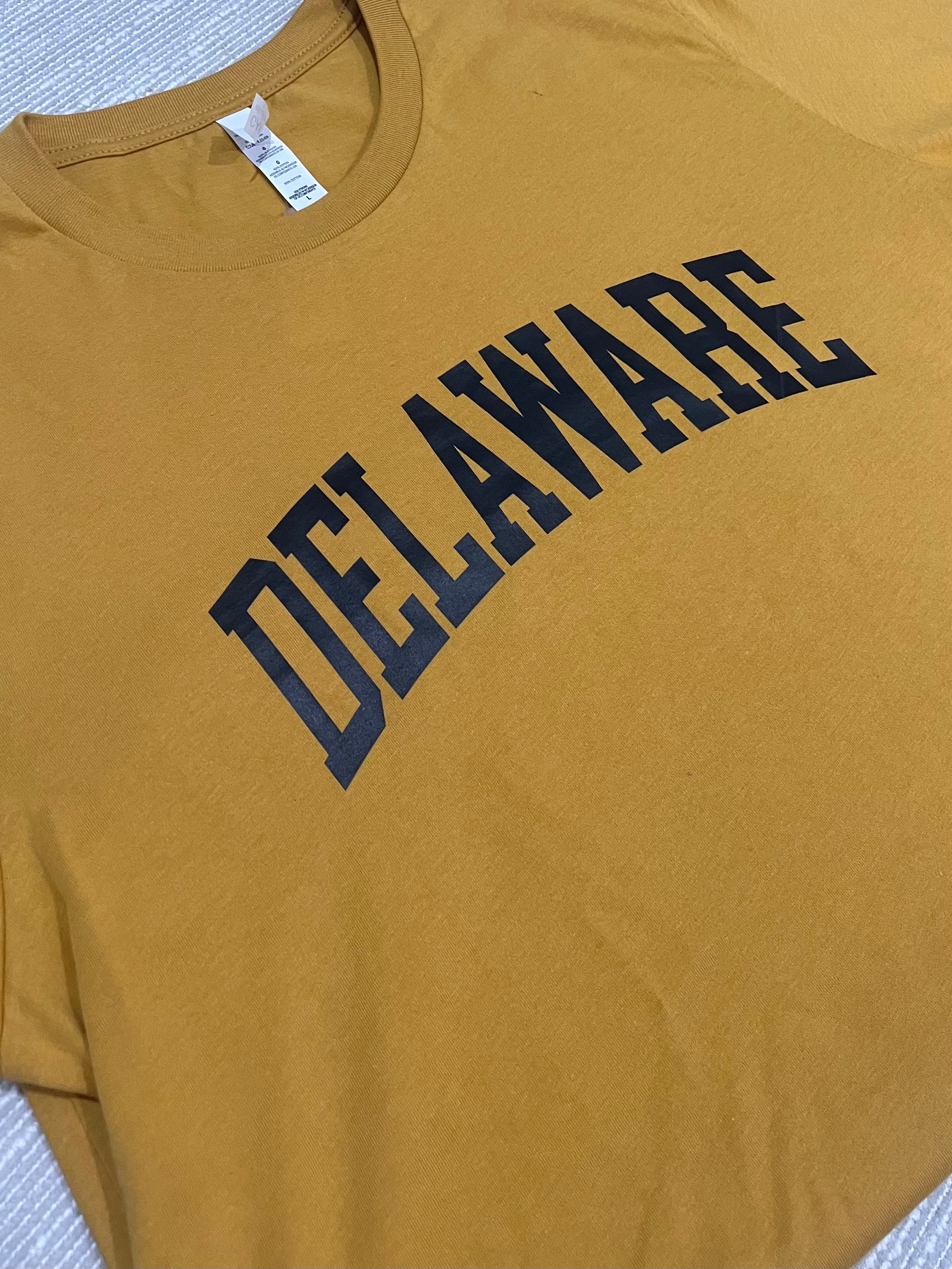 Yellow t-shirt with 'DELAWARE' printed in black on a textured surface