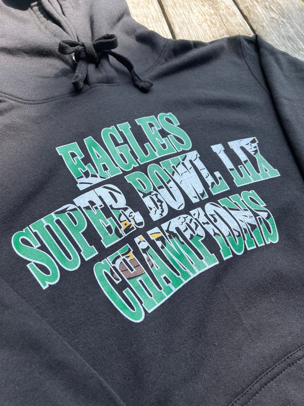 Black hoodie with 'Eagles Super Bowl LII Champions' text on a wooden surface