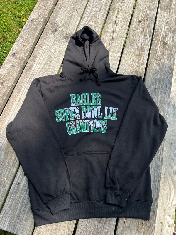 Black hoodie with 'Eagles Super Bowl LII Champions' text on a wooden surface