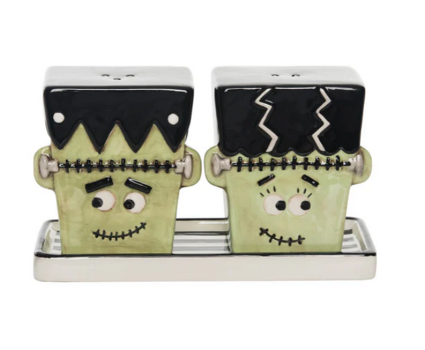 A set of two salt and pepper shakers designed to look like a Frankenstein and his bride, with a plate set included. The shakers are black, green and white with decorative details.