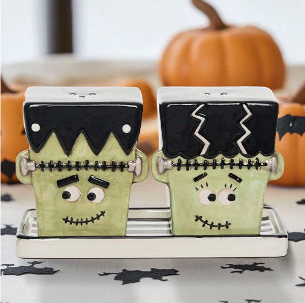 Halloween-themed Frankenstein salt and pepper shakers on a decorative stand with pumpkins in the background.