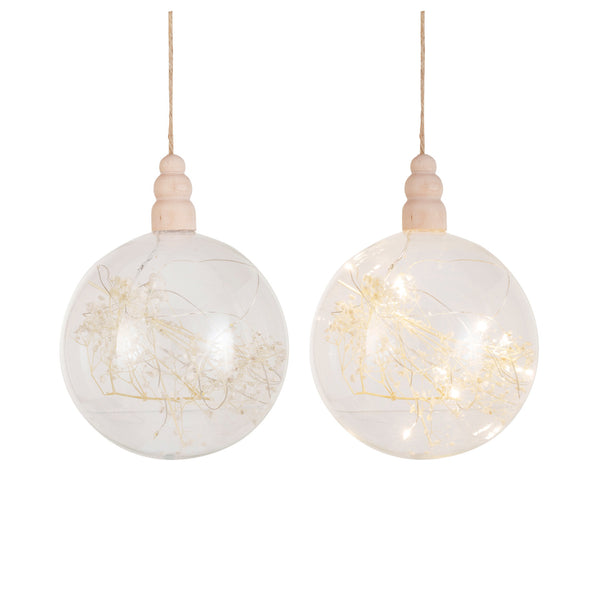 Two spherical glass LED ornaments with dried botanicals inside, hanging by strings, with a pine wood base.