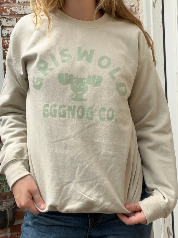 Person wearing a beige sweatshirt with 'Griswold Eggnog Co.' text and graphic.