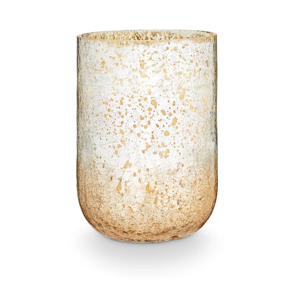 A large radiant glass candle with a two-tone metallic finish, predominantly in shades of beige and white.