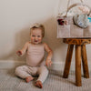 Baby sitting on the floor next to a wooden stool with a basket on top