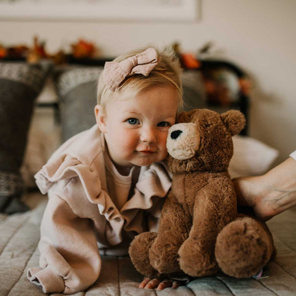 Child holding a teddy bear in a cozy indoor setting