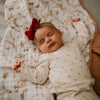 Baby sleeping on a floral blanket with a red bow headband