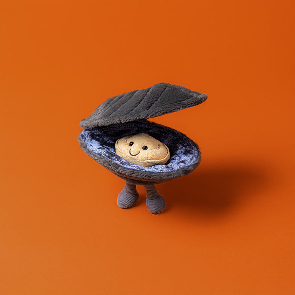 Toy figure of a clam with a smiling shell on an orange background