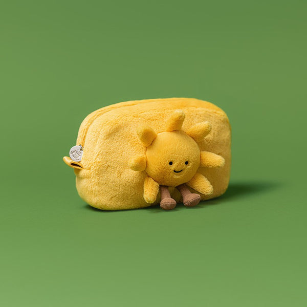 Yellow plush sun-shaped pouch with a smiling sun face on a green background