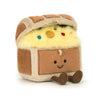 Plush toy resembling a character with a smiling face, brown and beige body, and colorful buttons on a white background.