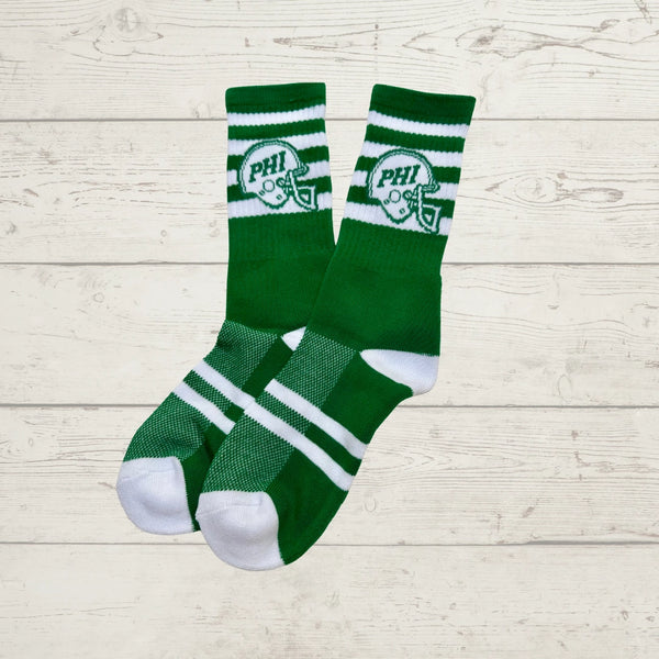 Green socks with white stripes and logo on a light wooden surface