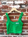 Green corduroy vest with 'Birds' logo on a hanger against a brick wall.