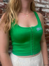 Person wearing a green ribbed crop top with 'Bulls' logo against a brick wall.