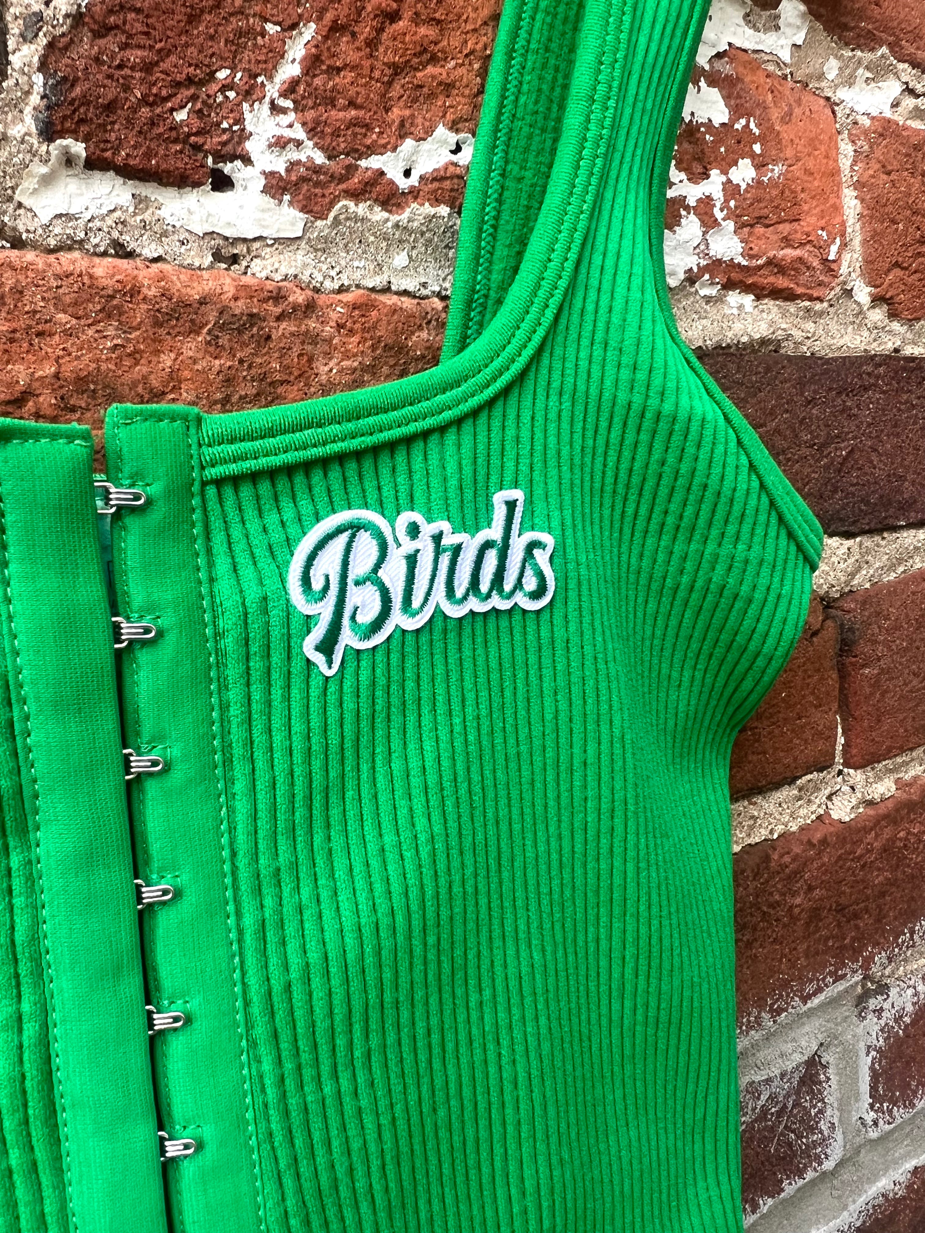 Green ribbed top with 'Birds' text against a brick wall