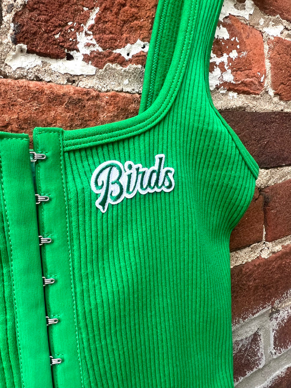 Green ribbed top with 'Birds' text against a brick wall