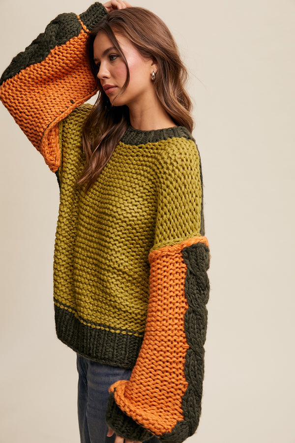 Woman wearing a green and orange sweater with patterned sleeves against a beige background