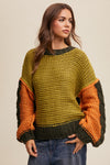 Woman wearing a green and orange chunky knit sweater on a beige background