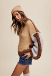Woman wearing a brown and beige sweater with denim shorts on a beige background