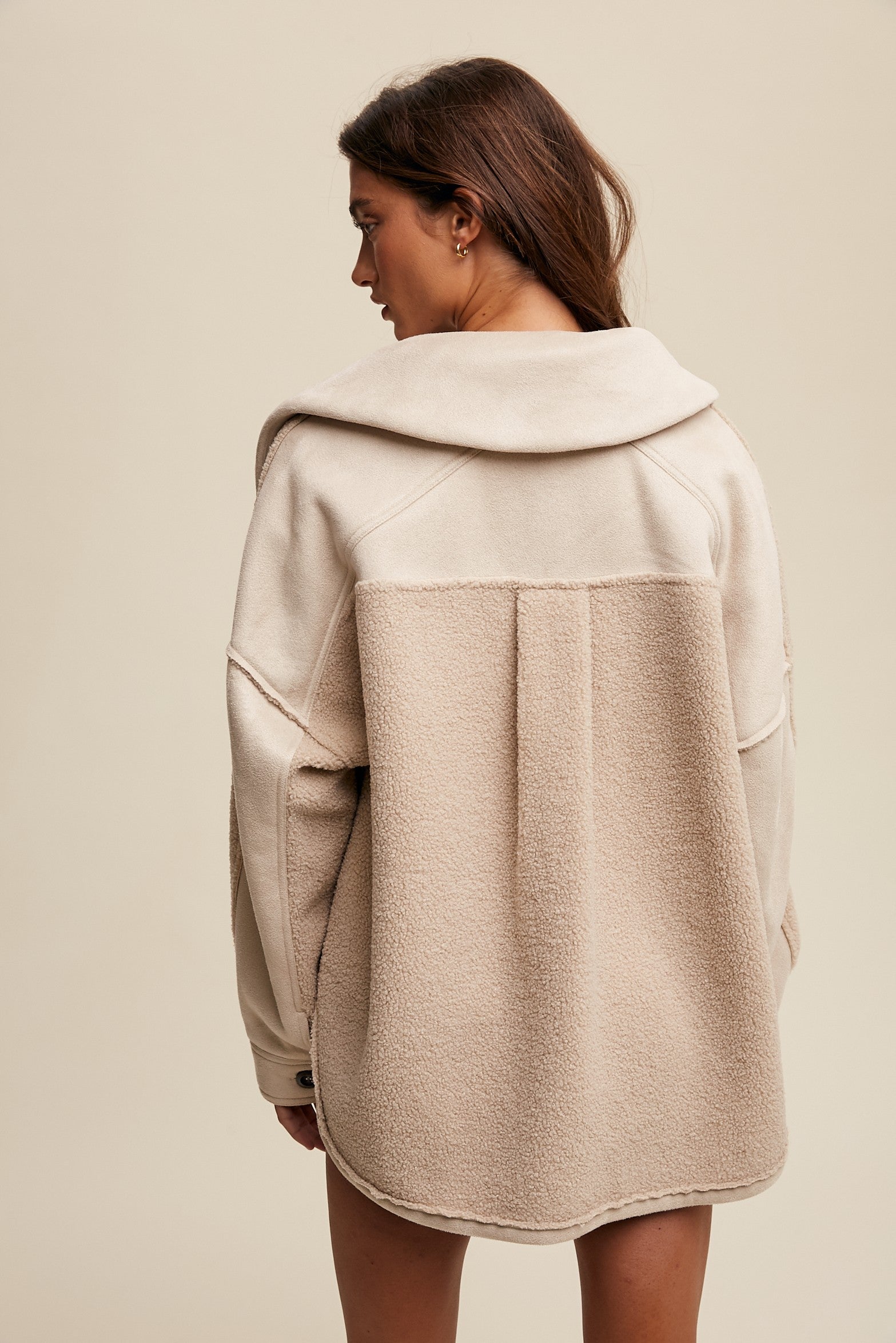 Woman wearing a beige hooded jacket on a plain background