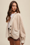 Woman wearing a beige cardigan with black buttons on a beige background