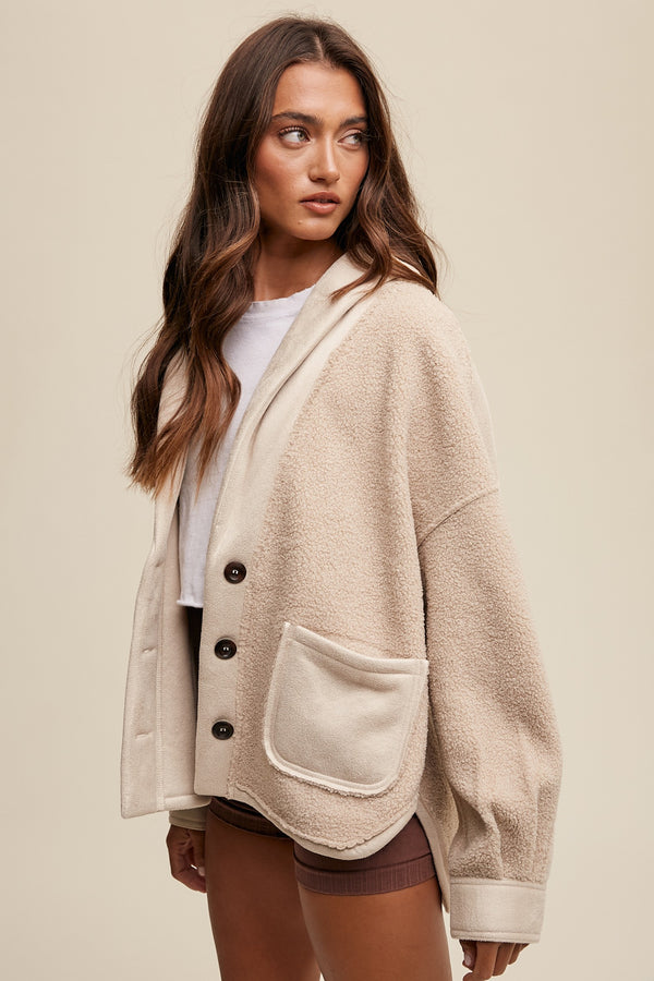 Woman wearing a beige cardigan with black buttons on a beige background