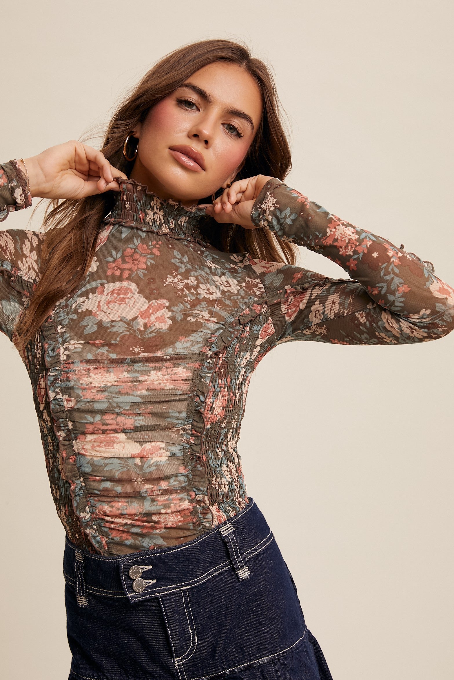 Woman wearing a floral long-sleeve top against a beige background