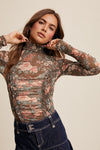 Woman wearing a floral long-sleeve top against a beige background
