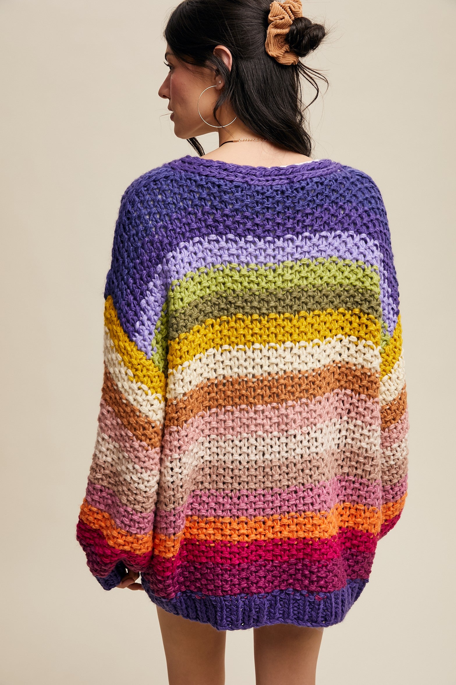 Woman wearing a colorful striped sweater against a plain background