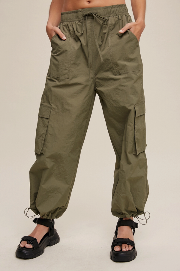 Person wearing olive green cargo pants on a plain background