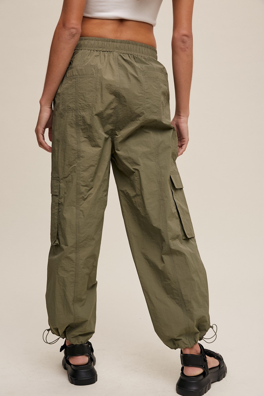 Person wearing olive green cargo pants on a plain background