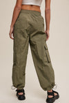 Person wearing olive green cargo pants on a plain background