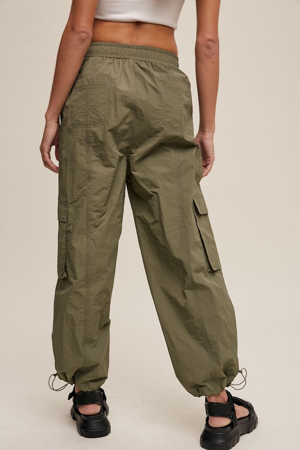 Person wearing olive green cargo pants on a plain background