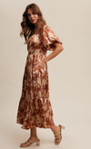 Woman wearing a patterned dress against a plain background