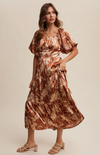 Woman wearing a patterned dress against a plain background