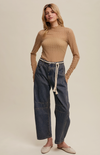 Woman wearing a ribbed sweater and wide-leg jeans on a plain background