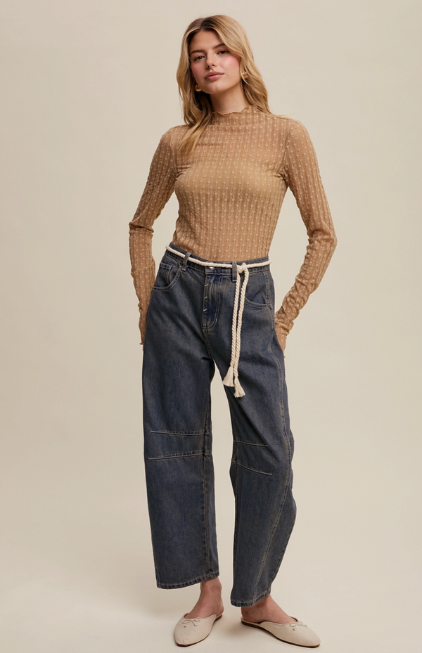 Woman wearing a ribbed sweater and wide-leg jeans on a plain background
