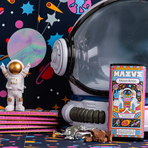 Space-themed display with astronaut figure, planet model, and MAEVZ Moon Rocks packaging.