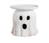 White ghost-shaped stool with black eye and mouth holes on a white background