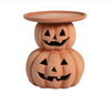 Wooden side table designed like a jack-o'-lantern with carved faces on a white background